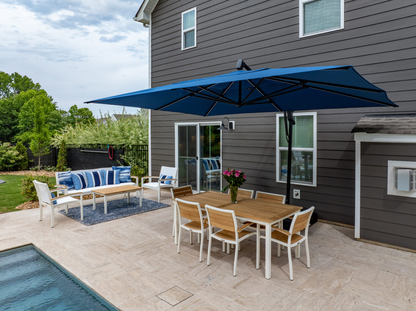 Outdoor chairs and a table under an awning next to a pool